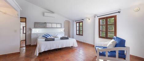 A bedroom with a bed, a chair, a window, and a door.