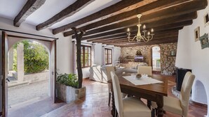 A spacious dining area with a rustic wooden ceiling and a chandelier, surrounded by stone walls and a fireplace. - Es Garroverar Villa: Luxurious Retreat in the Heart of Majorca (Pollensa)