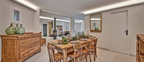 A dining area with a wooden table set for six, surrounded by wooden chairs. A wooden buffet stands to the left, and a mirror hangs on the wall to the right.