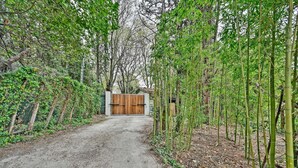 Een onverhard pad dat leidt naar een houten poort, omgeven door bamboe en ander groen.