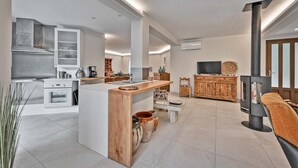 Een moderne keuken met een centraal kookeiland, inbouwapparatuur en een houtkachel.