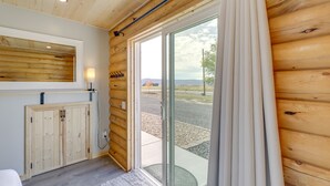 A wooden interior with a sliding glass door leading to an outdoor area, a built-in cabinet, and a small window. - Secluded Grand Junction Getaway w/ Sweeping Views! (Grand Junction)