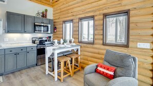A log cabin interior with a kitchen, dining area, and a gray sofa with a red pillow. - Secluded Grand Junction Getaway w/ Sweeping Views! (Grand Junction)