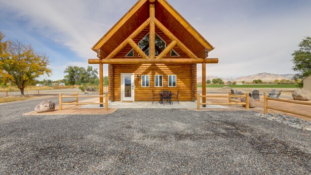 A log cabin with a triangular roof, a front door, and a patio area with outdoor seating. - Secluded Grand Junction Getaway w/ Sweeping Views! (Grand Junction)