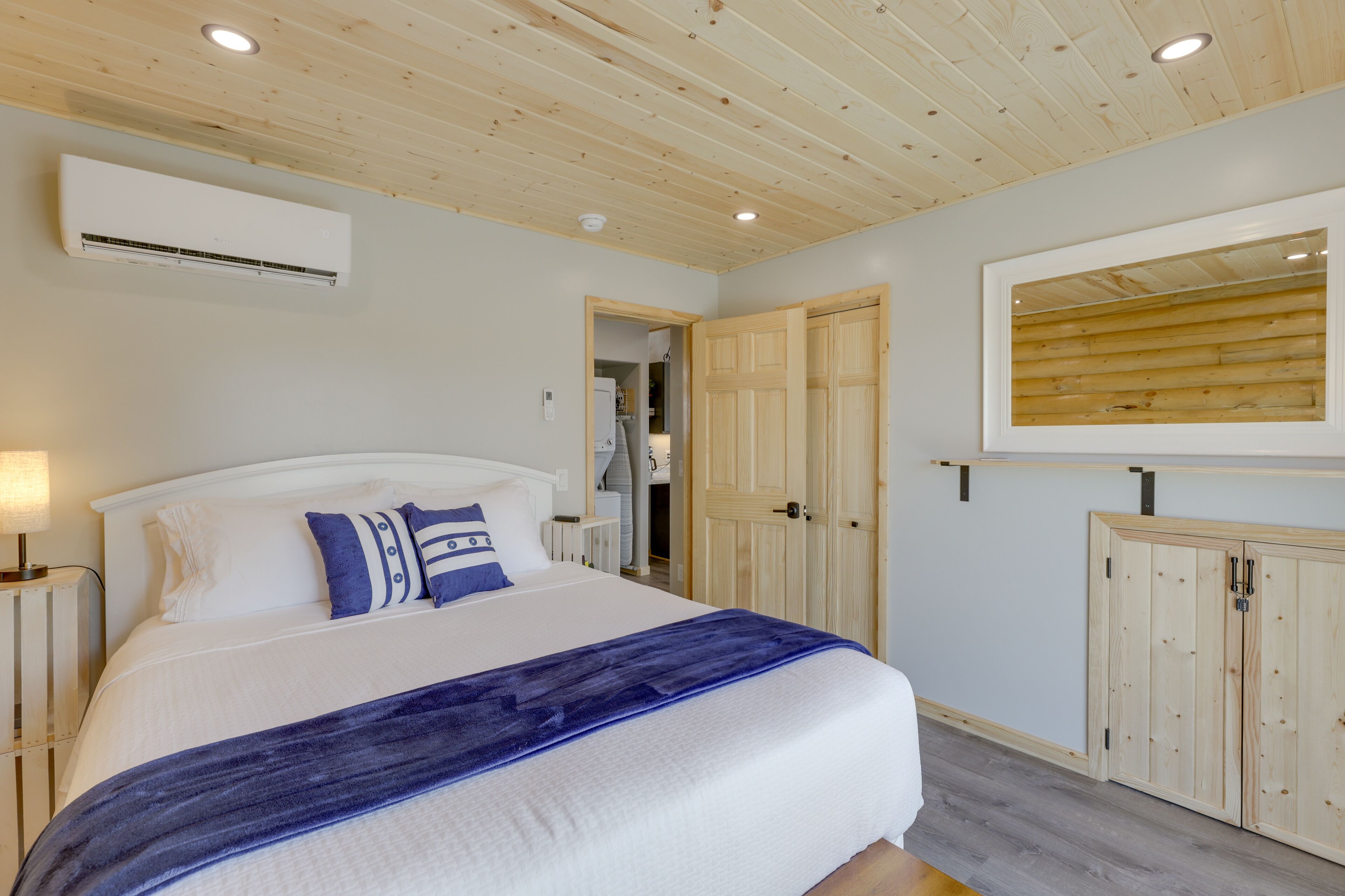 A bedroom with a bed, wooden ceiling, wardrobe, and a mirror.