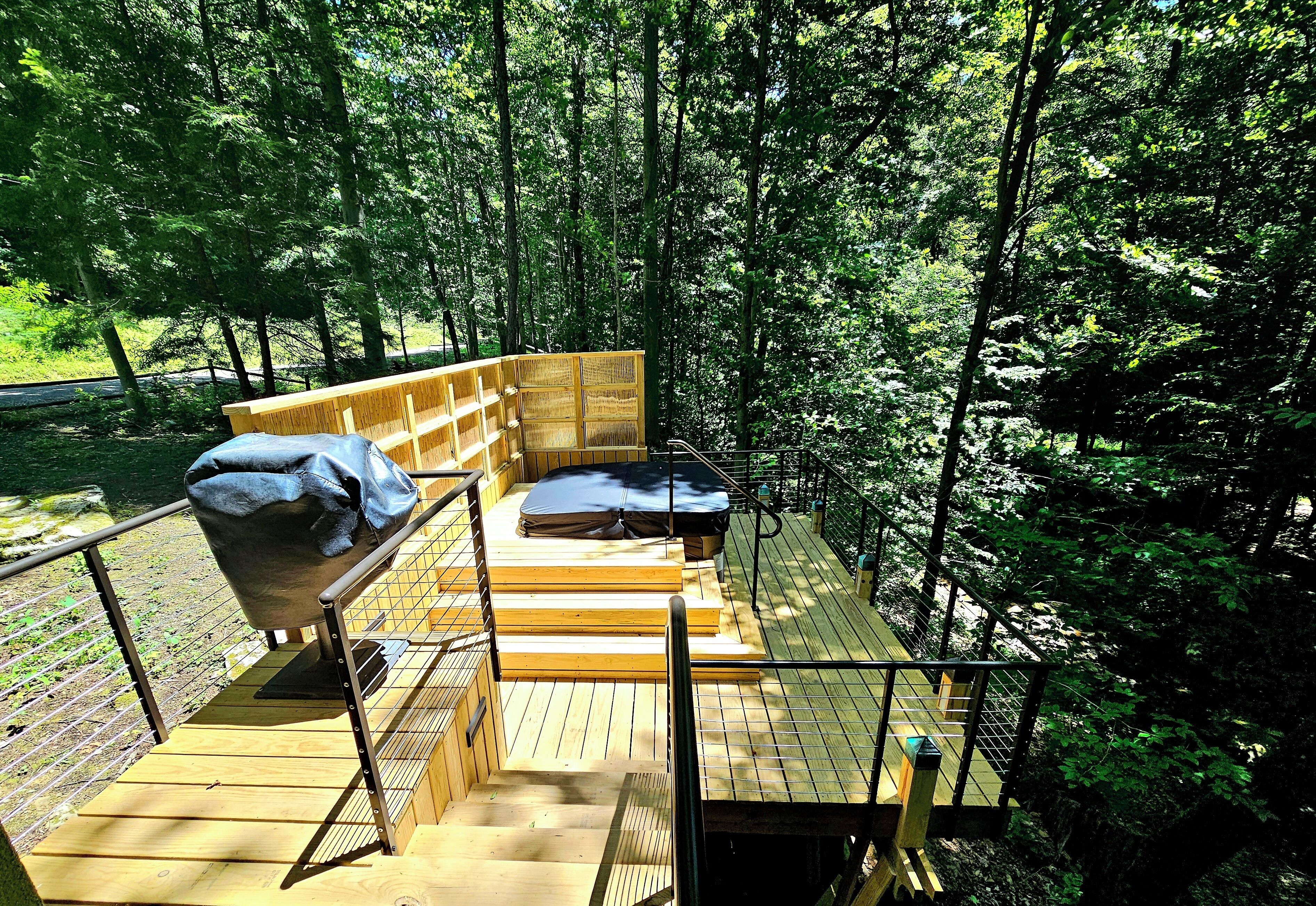 A wooden deck with a seating area, surrounded by trees.