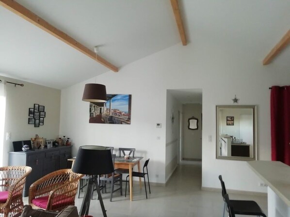 A spacious living area with a dining table, chairs, a lamp, and a painting on the wall.