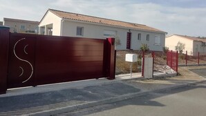 A gated residential area with houses, a closed gate, and a mailbox. - Cosy home (Bassillac et Auberoche)