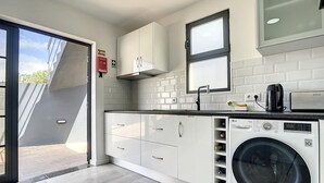 Una cocina moderna con armarios blancos, lavadora integrada y una ventana sobre el fregadero.