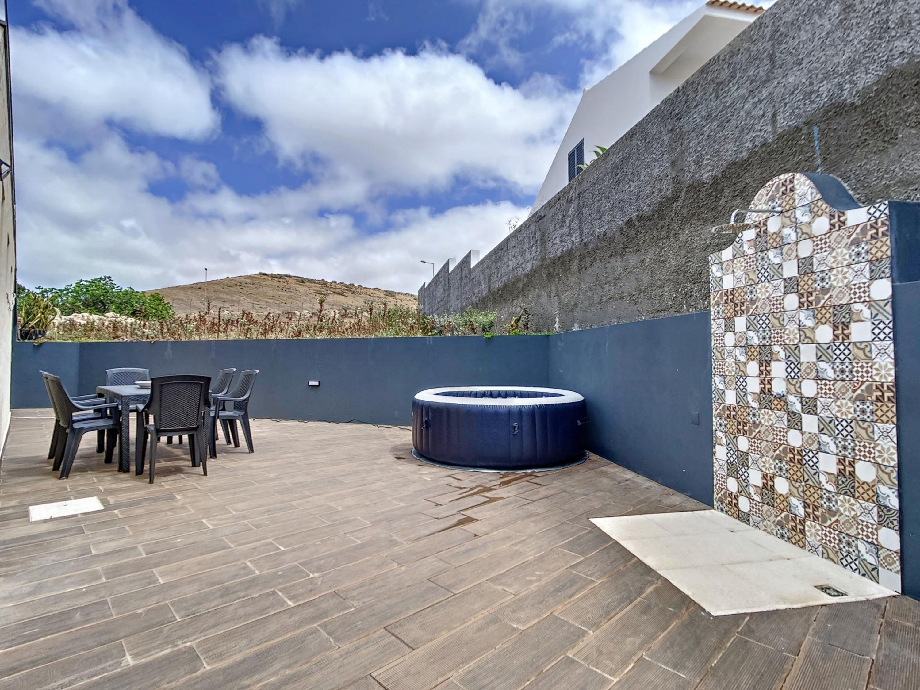 Eine Außenpatio mit Sitzgelegenheit, einem Whirlpool und einer Zierwand.