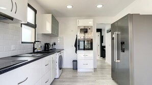 Una cocina moderna con gabinetes blancos, un refrigerador de acero inoxidable y un horno empotrado.