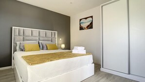 Un dormitorio moderno con una cama grande, una lámpara de noche y una obra de arte con forma de corazón en la pared.