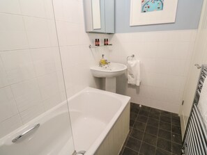 A bathroom with a bathtub, a sink, and a towel rack. - Bumbles (Padstow)