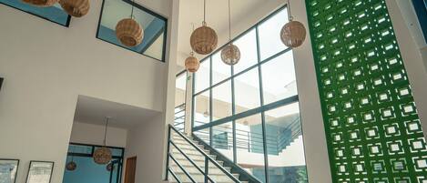 A modern interior with a staircase, hanging wicker light fixtures, and a green decorative wall.