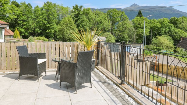 A patio with wicker furniture and a view of a mountain range. - Ben View (Arrochar)