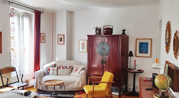 A living room with a sofa, yellow armchair, wooden cabinet, and a globe on a table.
