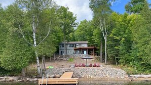 A lakeside cabin with a dock, surrounded by trees, and a deck with chairs. - Lakeview Retreat - Three Bedroom Cottage, Sleeps 6 (Kinmount)