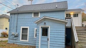 A single-story house with a blue exterior, a front door, and a small porch. - Beachside Apt 1 (Frankfort)