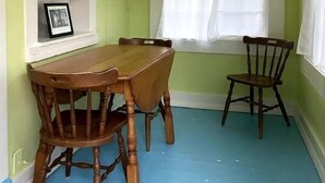 A dining area with a table and chairs, a window with curtains, and a shelf with a framed picture. - Beachside Apt 2 (Frankfort)