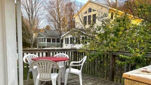 A wooden deck with a table and chairs, a wooden fence, and a yellow house in the background. - Beachside Apt 2 (Frankfort)