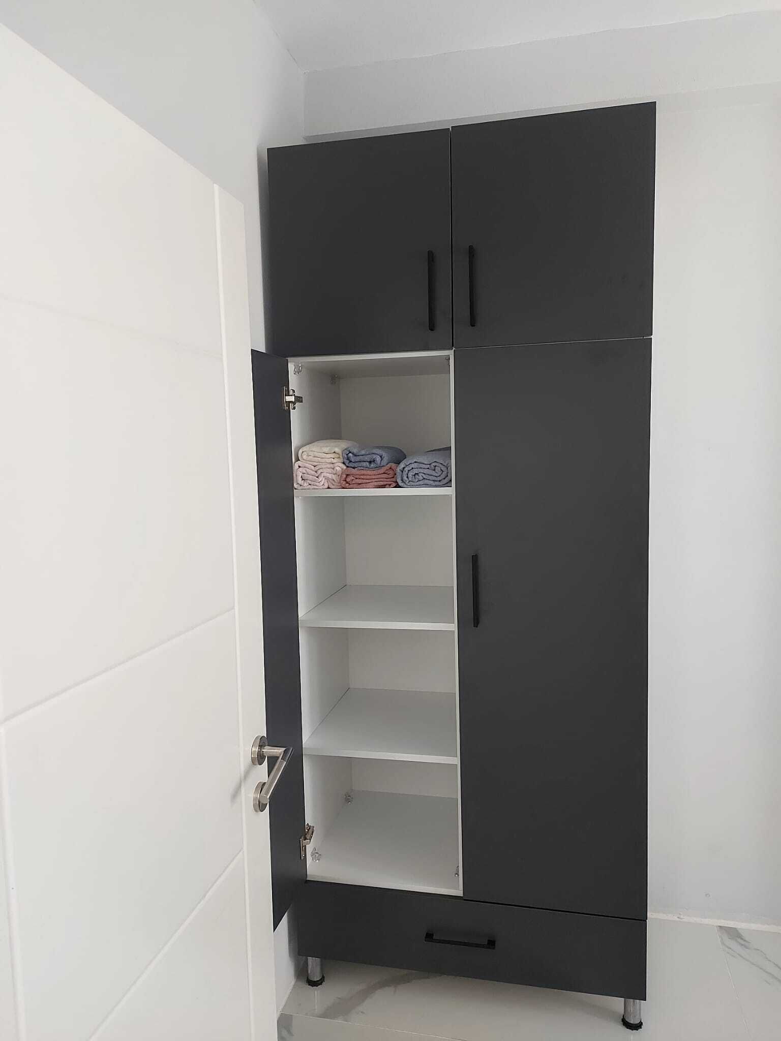 A dark-colored wardrobe with multiple shelves and a door.