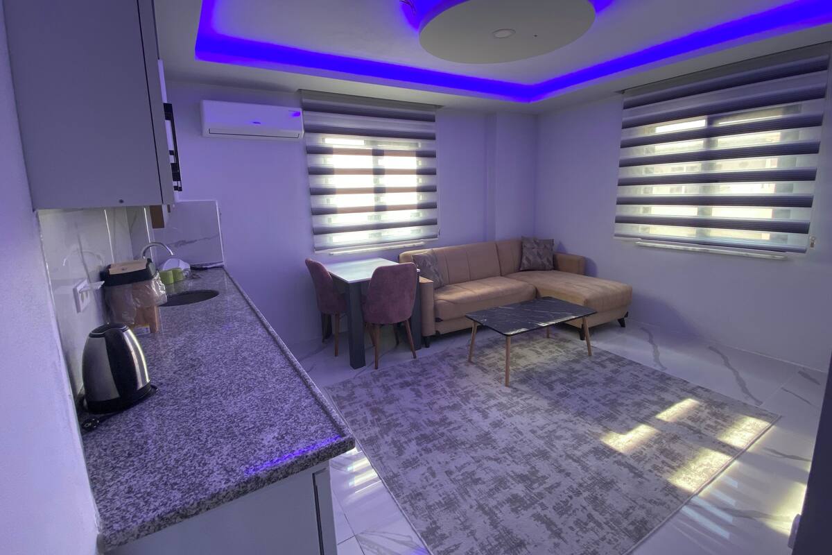 A modern living room with a sofa, coffee table, and a dining area.