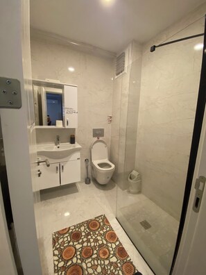Un baño moderno con inodoro, lavamanos y ducha.