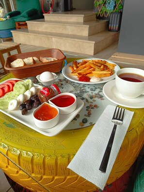 A table with a variety of food items including bread, cheese, olives, and condiments, along with a plate of fries and a cup of tea. - Fatih Apart Otel (Trabzon)