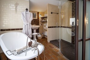 Un baño con bañera independiente, lavamanos y cabina de ducha con mampara de vidrio.