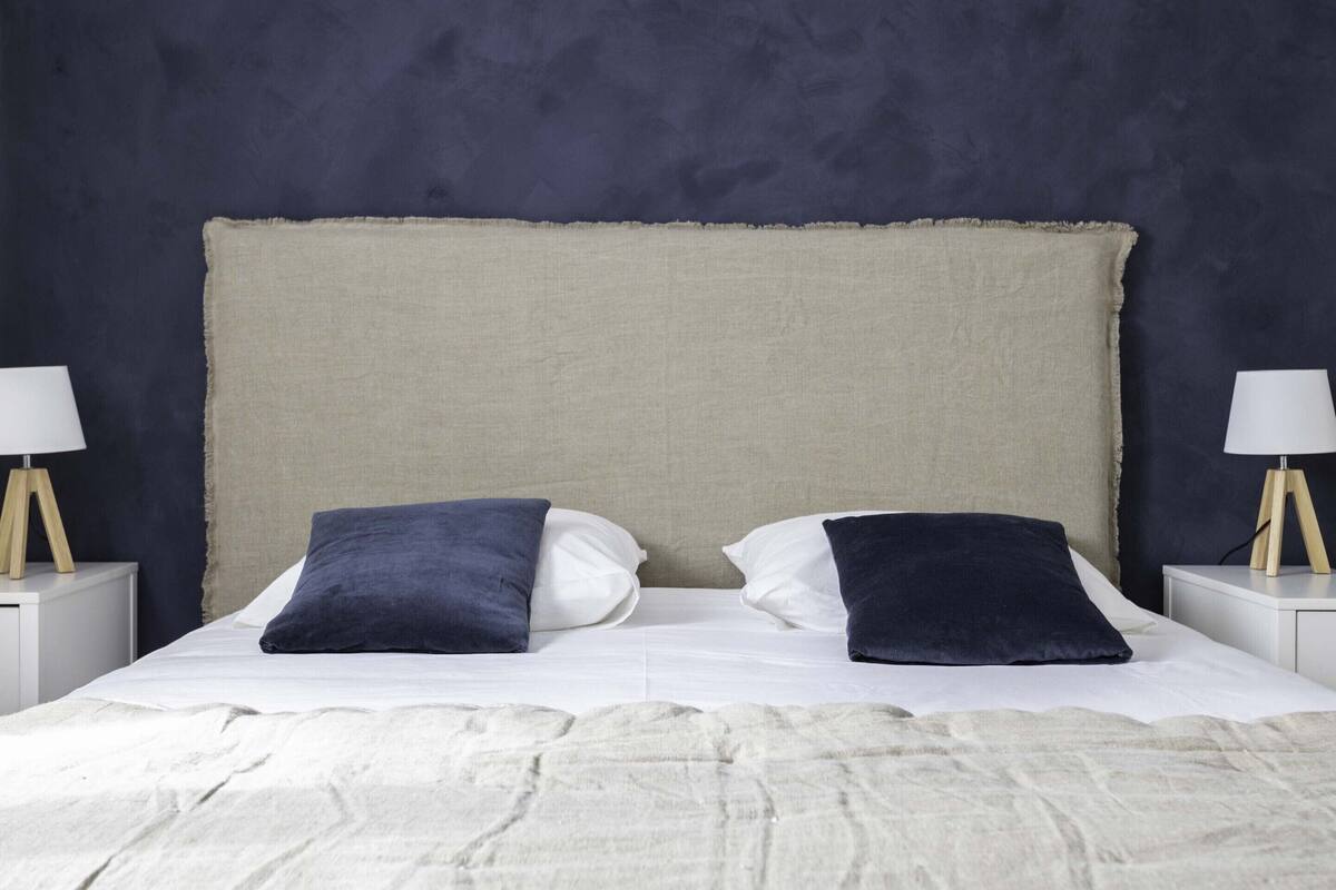 A bed with a large headboard, two bedside tables with lamps, and a textured blanket.
