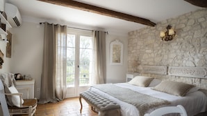 Ein Schlafzimmer mit Steinwand, einem Bett mit weißer Bettwäsche, einer Bank und einem Stuhl.