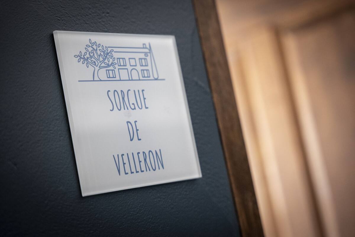 A sign with a building illustration and the text "SORGUE DE VELLERON".
