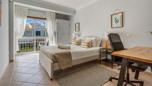 Ein Schlafzimmer mit Bett, Nachttisch, Stuhl und Blick ins Freie.
