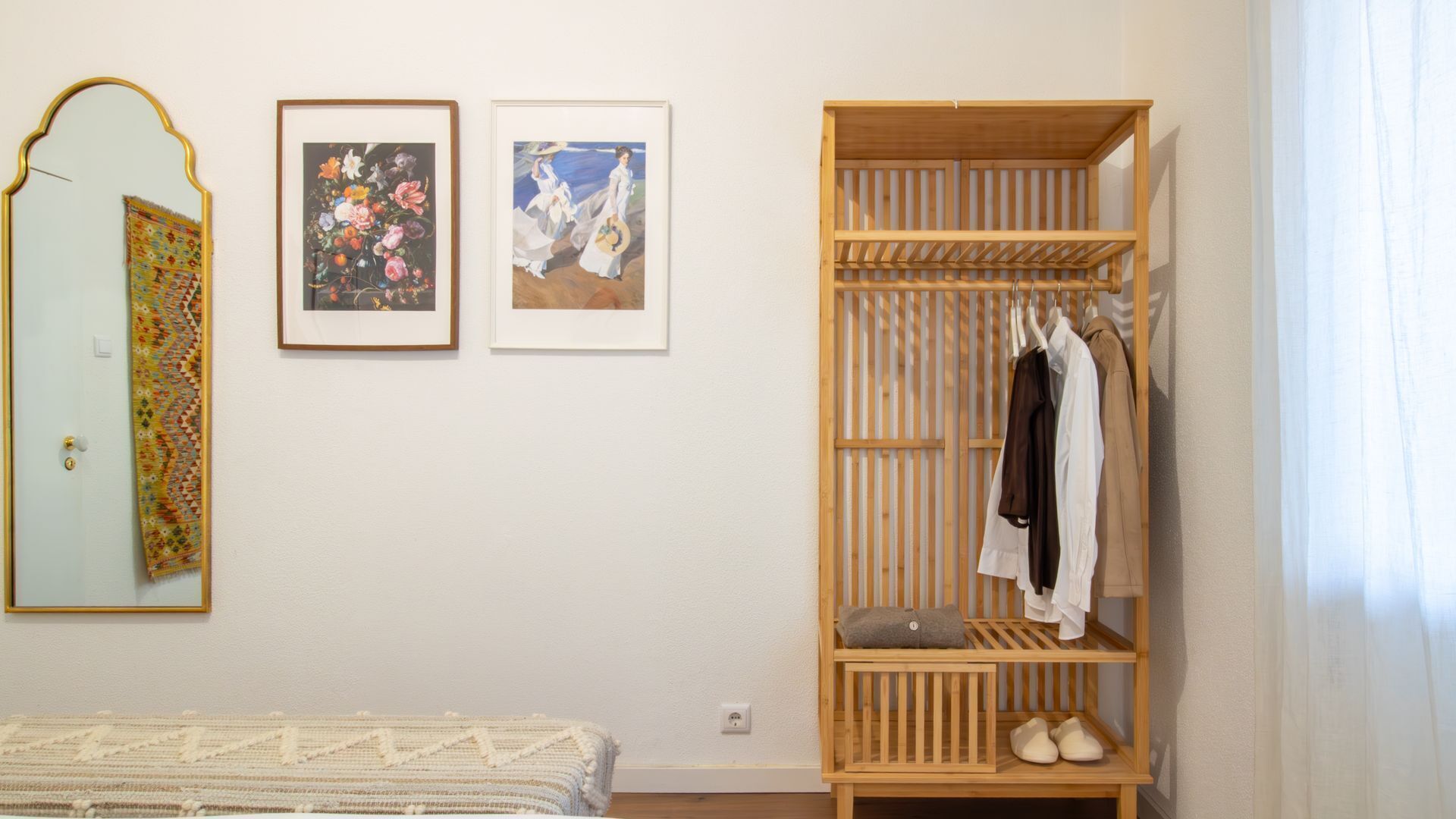 A bedroom with a bed, a wardrobe, and two framed pictures on the wall.