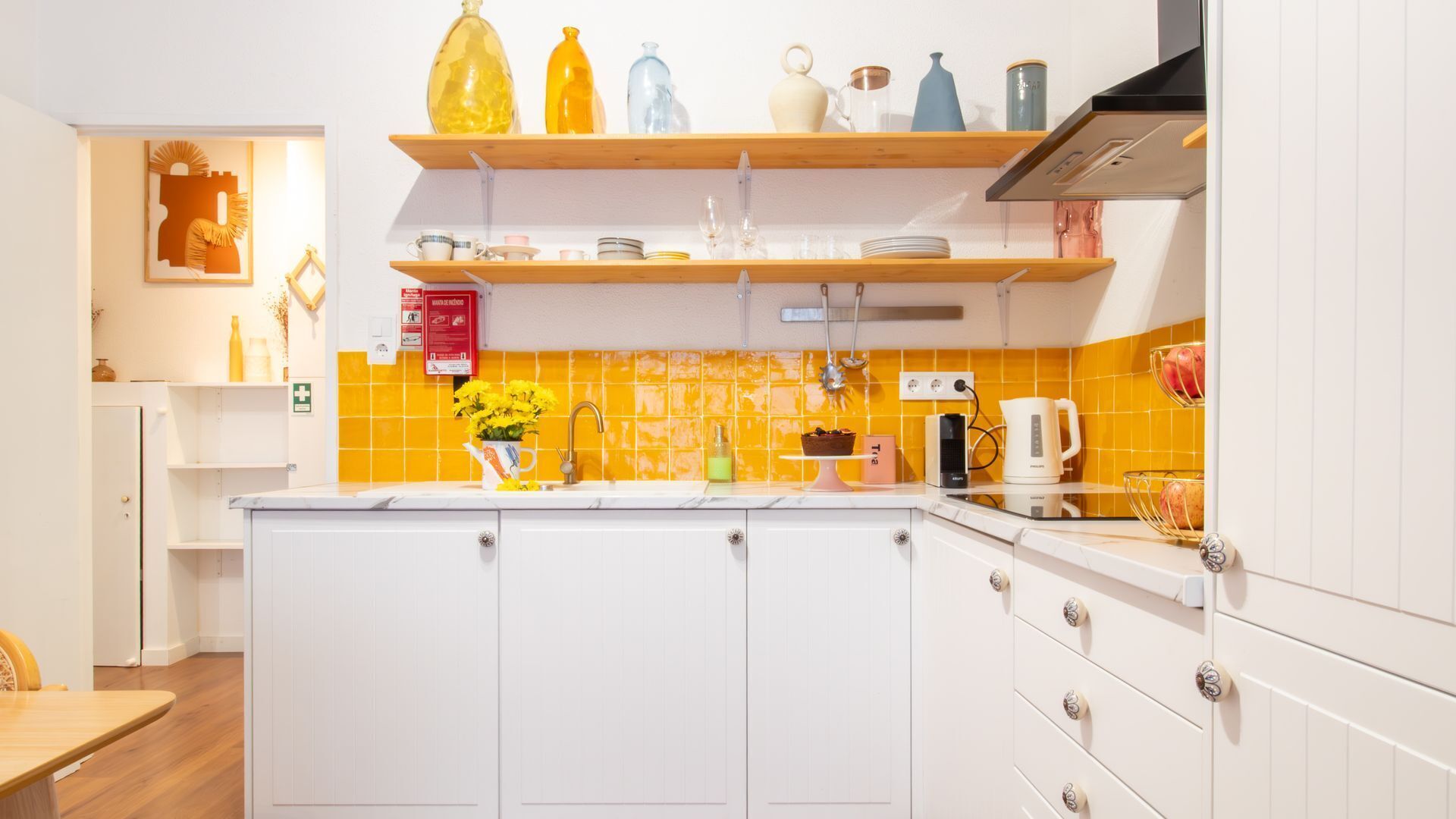 A kitchen with white cabinets, a yellow-tiled backsplash, and various kitchen appliances.