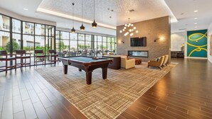 A spacious indoor area with a pool table, seating, and a TV mounted on a brick wall.