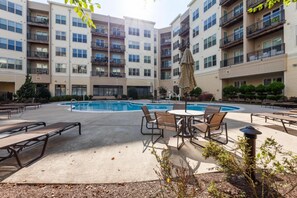 Un immeuble résidentiel à plusieurs étages doté d’une cour intérieure comprenant une piscine, un espace salon extérieur et une pergola.