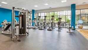 A gym with various exercise equipment, large windows, and a blue and white color scheme.