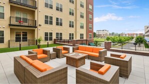 A multi-story building with outdoor seating areas, a pool, and a view of a park.