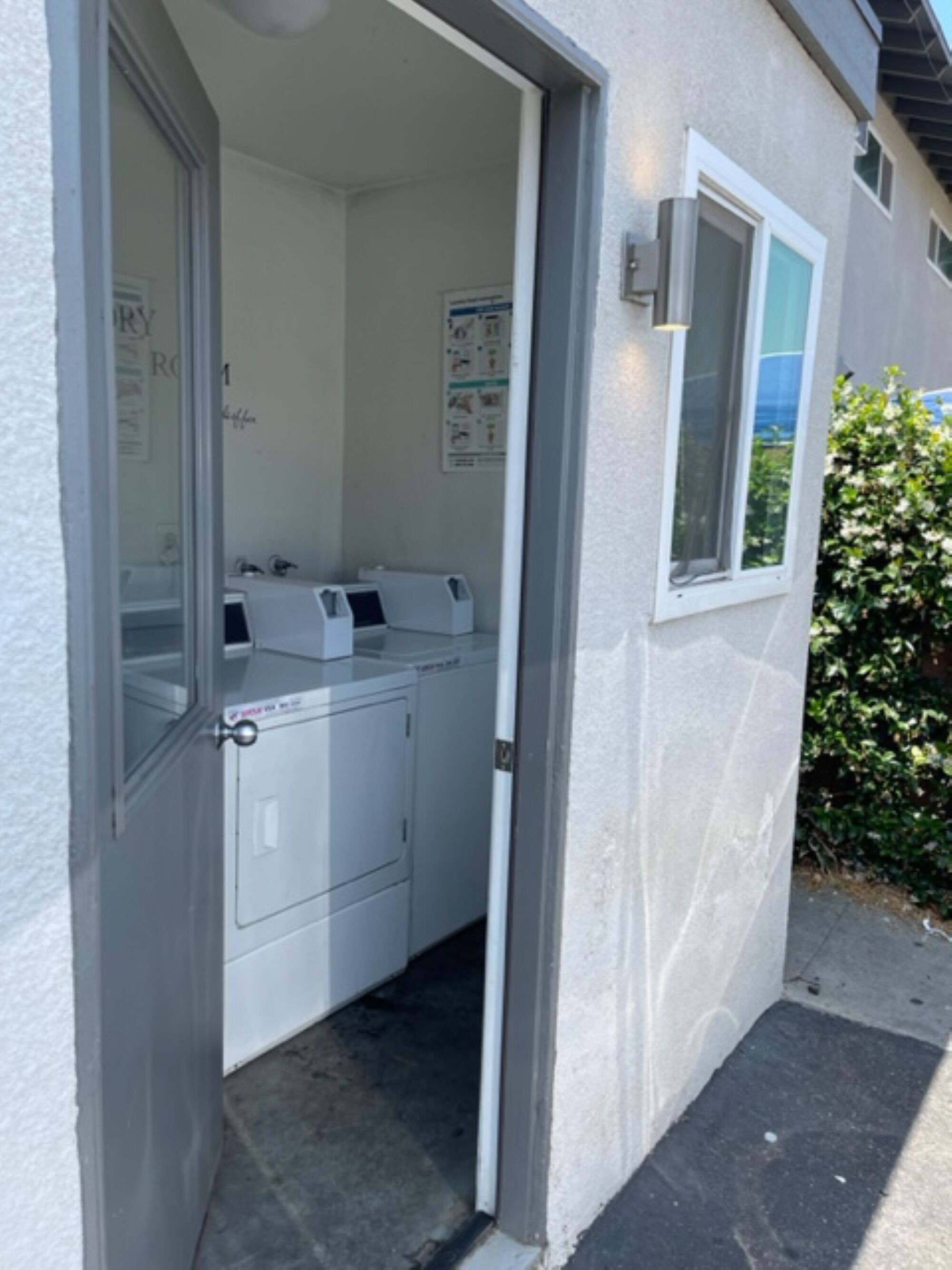 A laundry room with a washing machine and dryer, a window, and a door leading to a hallway.