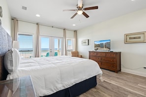 Une chambre à coucher comprenant un lit, une commode, un ventilateur de plafond, une fenêtre et un balcon.