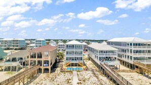 Un hôtel situé en bord de mer, composé de plusieurs bâtiments, avec une plage de sable fin et un ciel dégagé.