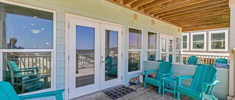 A covered deck with turquoise chairs and a wooden ceiling.