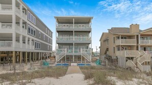 Een gebouw aan het strand met meerdere balkons en een centrale trap.