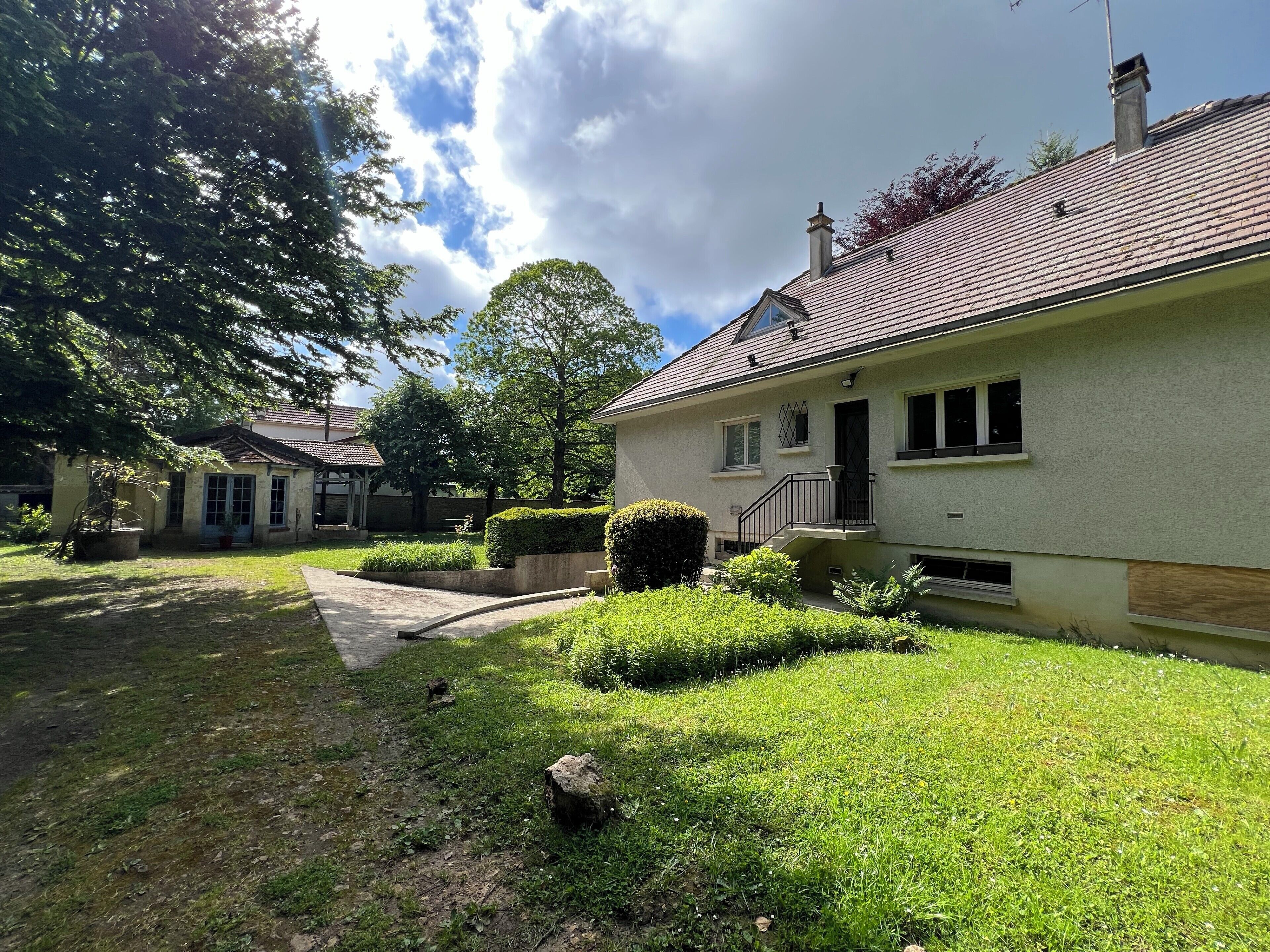A two-story house with a well-maintained lawn, a small garden, and a visible chimney.
