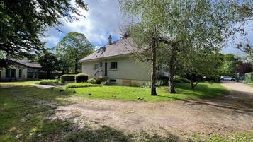 Ein zweistöckiges Haus mit einer Veranda, einem kleinen Garten und einem gepflasterten Einfahrtsweg.