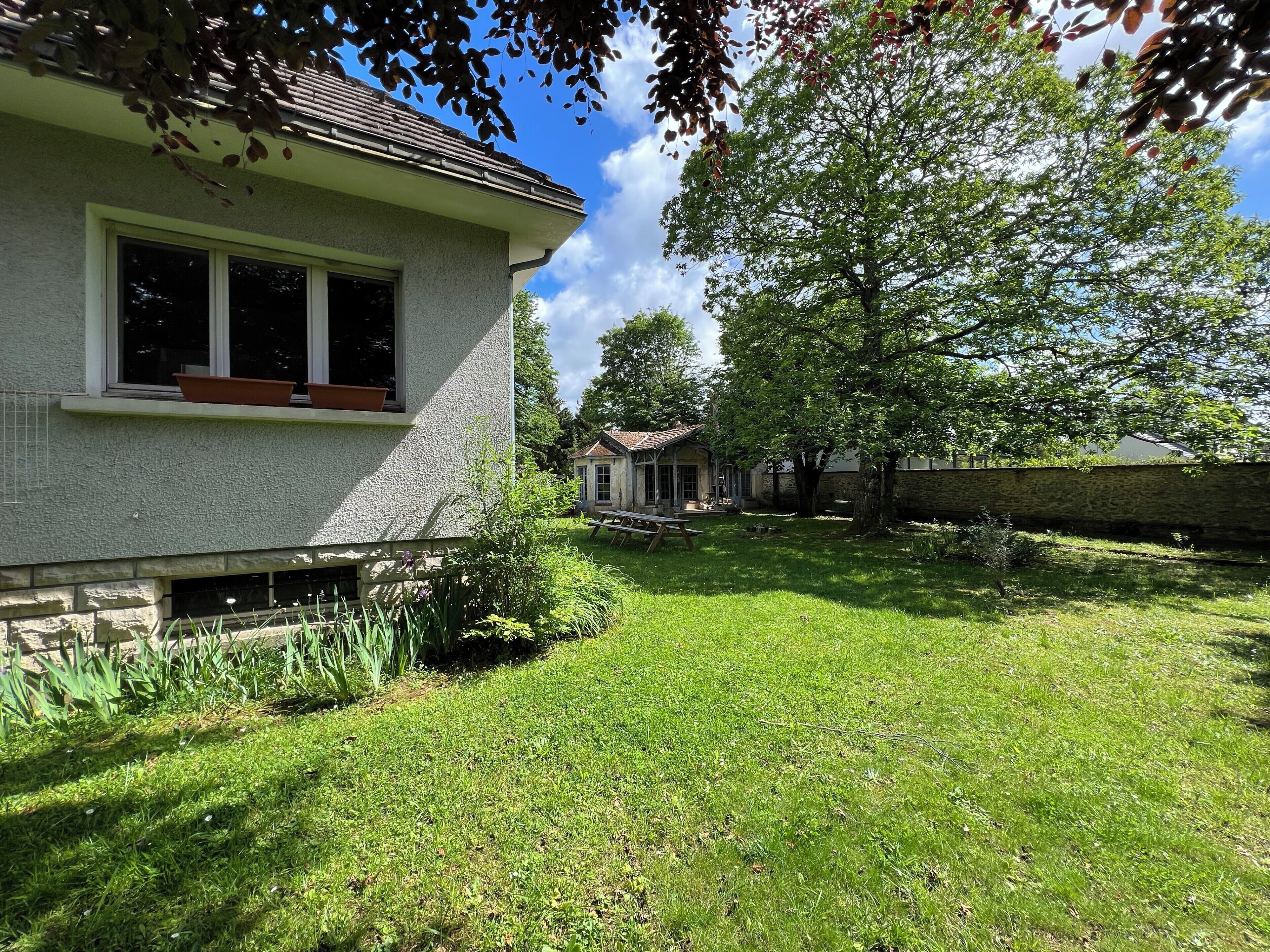 A house with a stone foundation, a large lawn, and a small patio area.