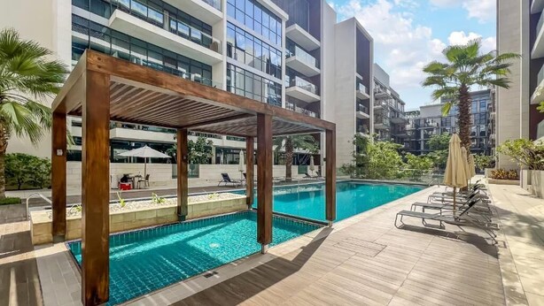 Un hôtel moderne doté d’une piscine, d’une pergola en bois et de chaises longues.