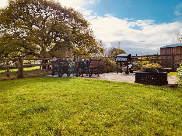 An outdoor seating area with wooden benches and a barbecue grill.