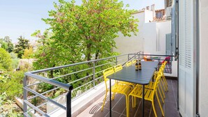 A balcony with a table and yellow chairs, a bottle of beer, and a tree in the background. - Maisonmars Le Concorde 3 (Marseille)